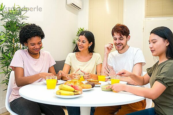 Multiethnische Freunde beim gesunden Frühstück zu Hause am gemeinsamen Tisch