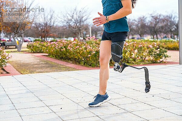 Seitenansicht des Unterkörpers einer behinderten Person mit Beinprothese beim Laufen in einem Stadtpark
