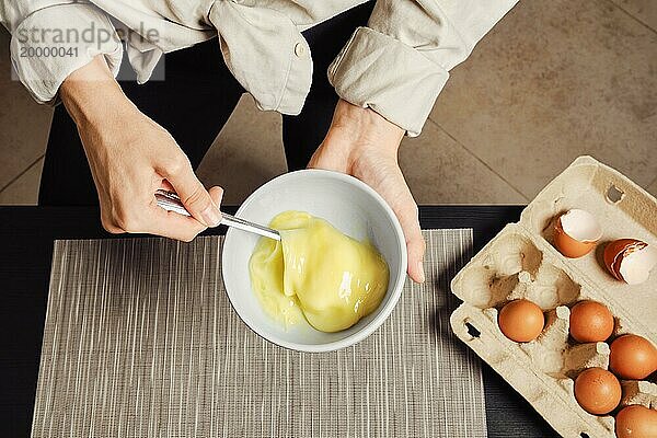 Draufsicht auf die Hände einer Frau  die Eier in einer Omeletteschale aufschlägt