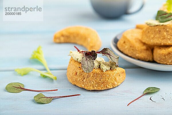 Hausgemachte gesalzene halbmondförmige Käseplätzchen  Tasse Kaffee auf blauem Holzhintergrund. Seitenansicht  selektiver Fokus