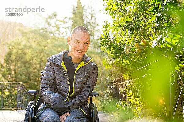 Porträt mit Kopierraum und Fokus auf einen fröhlichen behinderten Mann im Rollstuhl in einem Park