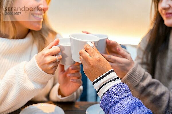 Nahaufnahme von Freunden  die in einer Cafeteria mit Kaffee anstoßen