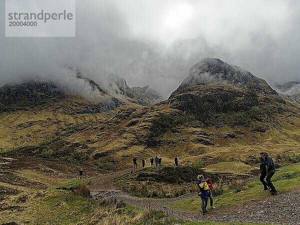 Personen vor bergigen  nebligen Landschaft mit Hügeln Three Sisters in Schottland  Großbritannien  Europa