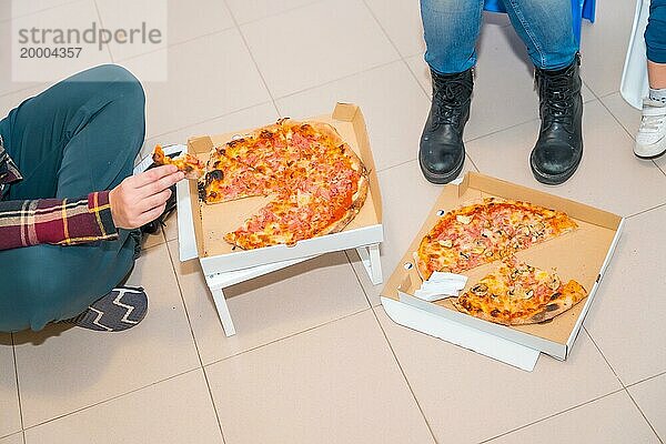 Draufsicht auf drei nicht erkennbare Personen  die in Bewegung Pizzen essen