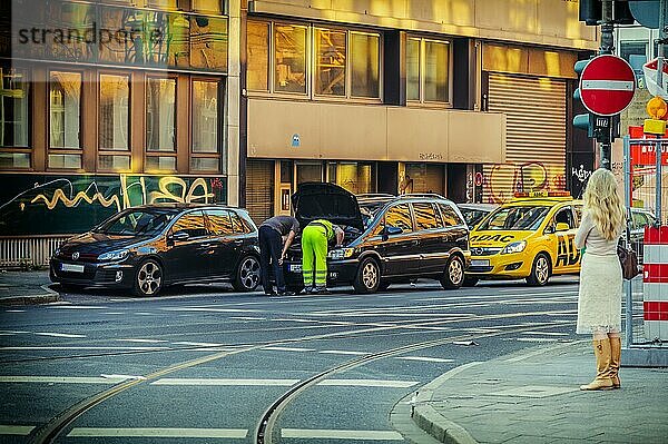 Eine Frau beobachtet 2 Männer  die ein Auto reparieren