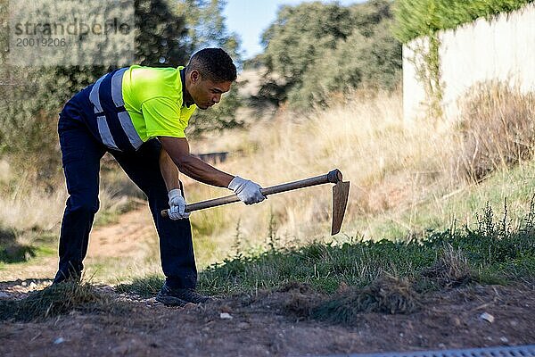 Porträt eines männlichen Latino Gärtners in Arbeitskleidung beim Graben im Boden