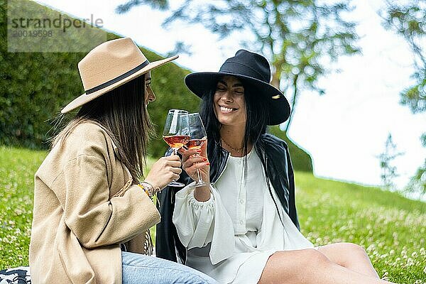 Porträt von zwei lustigen Freunden  die sich beim Weintrinken und Lachen im Park amüsieren