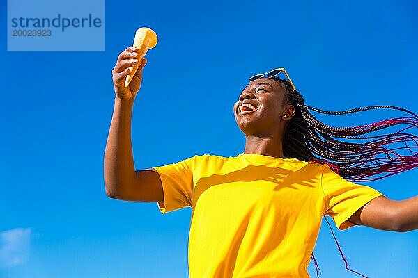 Niedriger Winkel Blick auf eine glückliche afrikanische Frau hält ein Eis im Freien
