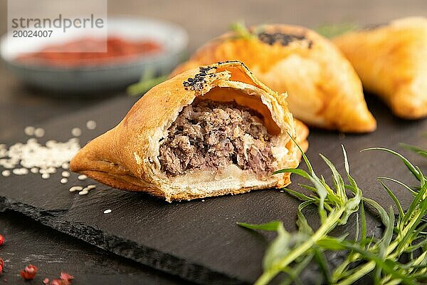 Hausgemachte asiatisches Gebäck Samosa auf schwarzem Beton Hintergrund. Seitenansicht  selektiver Fokus