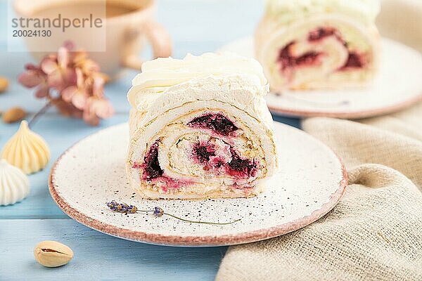 Biskuitrolle mit Frischkäse und Marmelade  Tasse Kaffee auf blauem Holzhintergrund und Leinenstoff. Seitenansicht  Nahaufnahme  selektiver Fokus