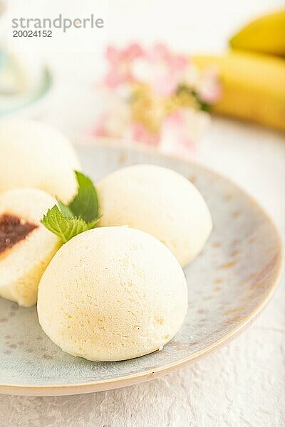 Japanischer Reis süße Brötchen Mochi mit Marmelade und Tasse Kaffee auf einem grauen Beton Hintergrund gefüllt. Seitenansicht  Nahaufnahme  selektiver Fokus