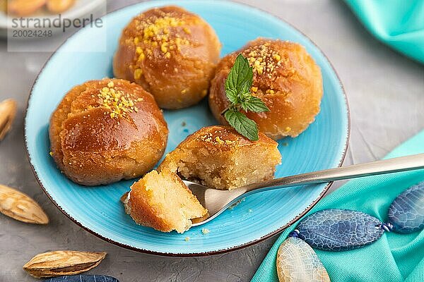 Hausgemachtes traditionelles türkisches Dessert Sekerpare mit Mandeln und Honig  Tasse grüner Tee auf grauem Betonhintergrund und blauem Textil. Seitenansicht  selektiver Fokus