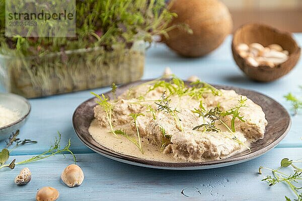 Geschmorte Hühnerfilets mit Kokosmilchsauce und Mizunakraut Mikrogrün auf blauem Holzhintergrund. Seitenansicht  Nahaufnahme  selektiver Fokus