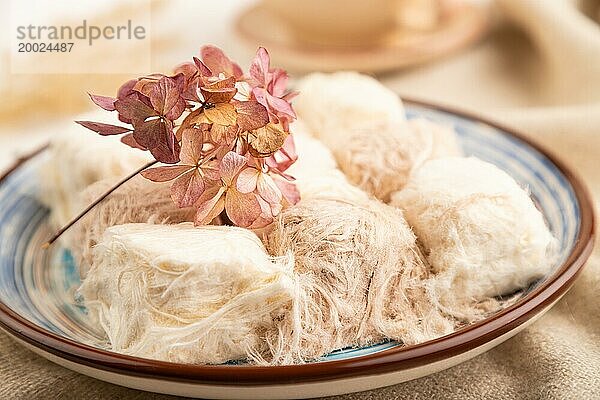 Traditionelle arabische Süßigkeiten Pishmanie und eine Tasse grüner Tee auf weißem hölzernem Hintergrund und Leinenstoff. Seitenansicht  Nahaufnahme  selektiver Fokus