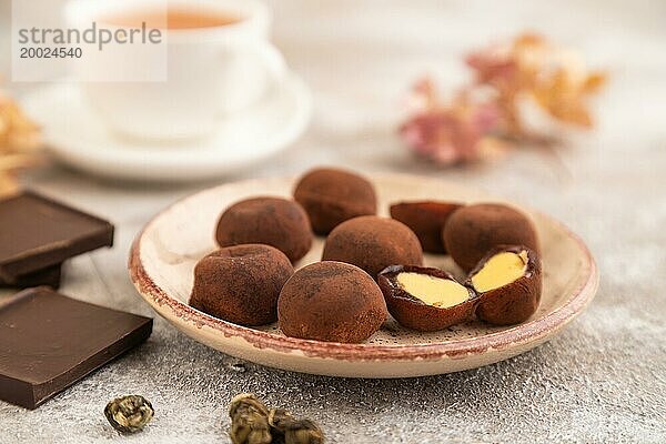 Japanischer Reis süße Brötchen Schokolade Mochi gefüllt mit Sahne und Tasse grüner Tee auf braunem Beton Hintergrund. Seitenansicht  Nahaufnahme  selektiver Fokus