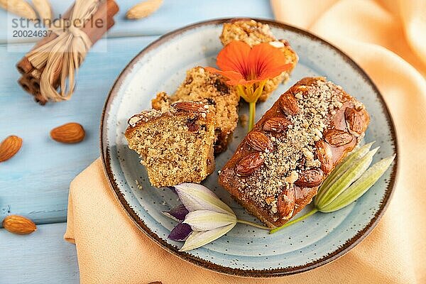 Karamell und Mandelkuchen mit Tasse Kaffee auf blauem Holzhintergrund und orangefarbenem Leinenstoff. Seitenansicht  Nahaufnahme  selektiver Fokus