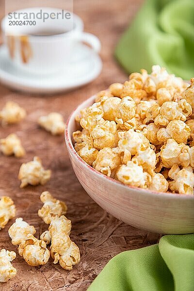 Popcorn mit Karamell in einer Keramikschale auf braunem Betonhintergrund und grünem Textil. Seitenansicht  Nahaufnahme  selektiver Fokus