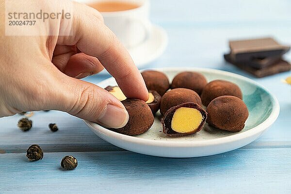 Japanischer Reis süße Brötchen Schokolade Mochi gefüllt mit Sahne und Tasse grüner Tee mit der Hand auf blauen hölzernen Hintergrund. Seitenansicht  Nahaufnahme  selektiver Fokus