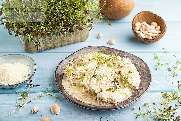 Geschmorte Hühnerfilets mit Kokosmilchsauce und Mizunakraut Mikrogrün auf blauem Holzhintergrund. Seitenansicht  Nahaufnahme  selektiver Fokus