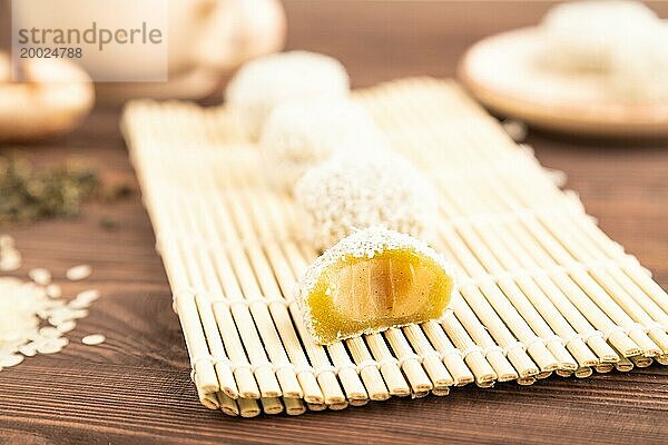 Japanischer Reis süße Brötchen Mochi gefüllt mit Pandan und Kokosnuss Marmelade und Tasse grüner Tee auf braunem Holz Hintergrund. Seitenansicht  Nahaufnahme  selektiver Fokus