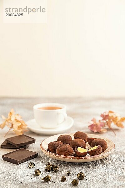 Japanischer Reis süße Brötchen Schokolade Mochi gefüllt mit Sahne und Tasse grüner Tee auf braunem Beton Hintergrund. Seitenansicht  Nahaufnahme  selektiver Fokus