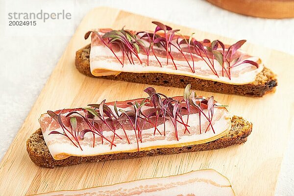 Brotsandwiches mit Dörrfleisch und Schmalz mit Rübenmikrogrün auf grauem Betonhintergrund. Seitenansicht  Nahaufnahme  selektiver Fokus