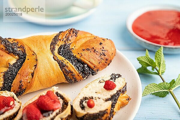 Hausgemachte süße Brötchen mit Erdbeermarmelade und Tasse grüner Tee auf einem blauen hölzernen Hintergrund. Seitenansicht  Nahaufnahme  selektiver Fokus