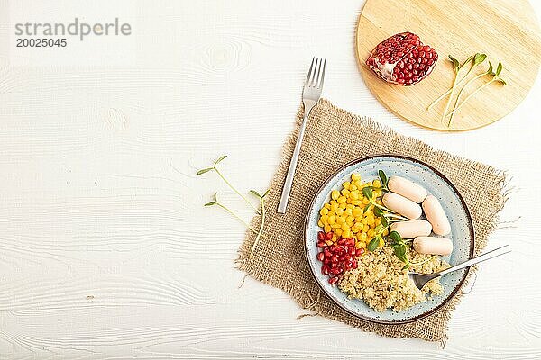 Gemischter Quinoa Brei  Mais  Granatapfelkerne und kleine Würstchen auf weißem Holzhintergrund. Draufsicht  flat lay  copy space. Lebensmittel für Kinder  gesundes Essen Konzept