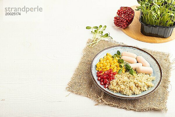 Gemischter Quinoa Brei  Mais  Granatapfelkerne und kleine Würstchen auf weißem Holzhintergrund. Seitenansicht  Kopie Raum. Lebensmittel für Kinder  gesundes Essen Konzept
