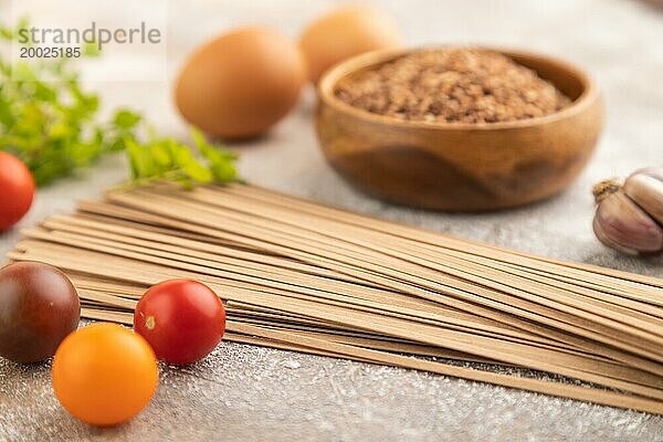 Japanische Buchweizen Soba Nudeln mit Tomaten  Eiern  Gewürzen  Kräutern auf braunem Betonhintergrund. Seitenansicht  Nahaufnahme  selektiver Fokus