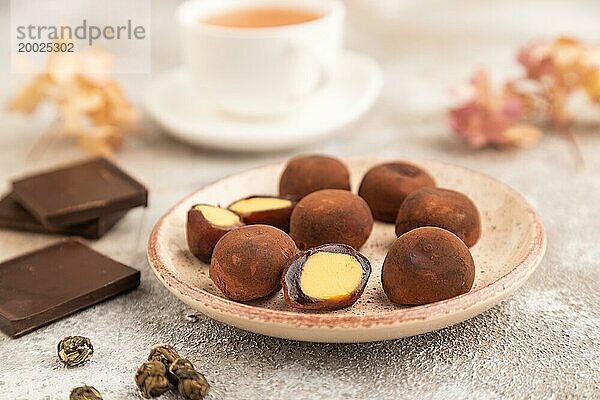 Japanischer Reis süße Brötchen Schokolade Mochi gefüllt mit Sahne und Tasse grüner Tee auf braunem Beton Hintergrund. Seitenansicht  Nahaufnahme  selektiver Fokus