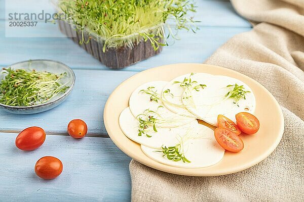 Weißer Käse mit Tomaten und Koriander Mikrogrün auf blauem Holzhintergrund und Leinenstoff. Seitenansicht  Nahaufnahme  selektiver Fokus