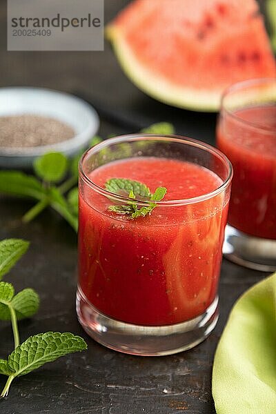 Wassermelonensaft mit Chiasamen und Minze im Glas auf einem schwarzen Betonhintergrund mit grünem Textil. Gesundes Getränk Konzept. Seitenansicht  Nahaufnahme  selektiver Fokus