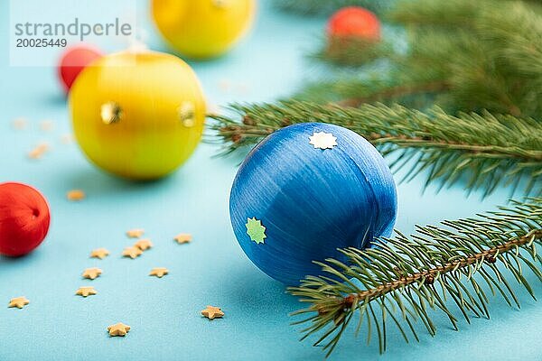 Weihnachten oder Neujahr Zusammensetzung. Dekorationen  blaue  rote  gelbe Kugeln  Tannen und Fichtenzweige  auf einem blauen Papierhintergrund. Seitenansicht  Nahaufnahme  selektiver Fokus