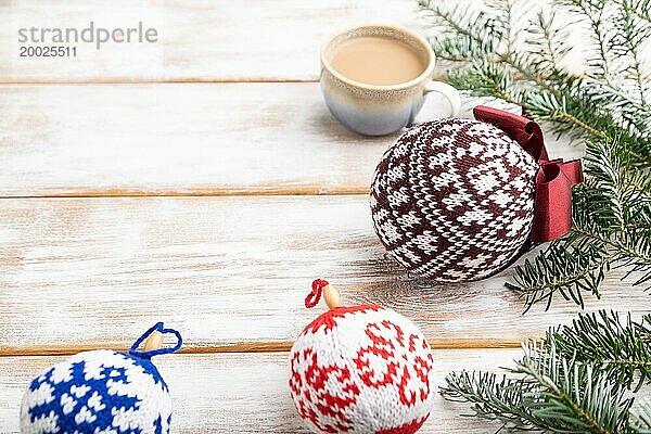 Weihnachten oder Neujahr Zusammensetzung. Dekorationen  gestrickte Kugeln  Tannen und Fichtenzweige  eine Tasse Kaffee  auf einem weißen Holzhintergrund. Seitenansicht  Kopierraum  selektiver Fokus