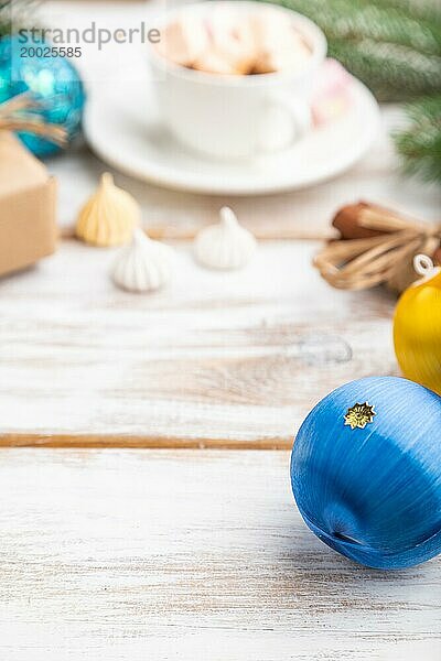 Weihnachten oder Neujahr Rahmen Zusammensetzung. Dekorationen  Box  Kugeln  Zimt  Bänder  Tannen und Fichtenzweige  Tasse Kaffee  auf einem weißen Holzhintergrund. Seitenansicht  copy space  selektiver Fokus