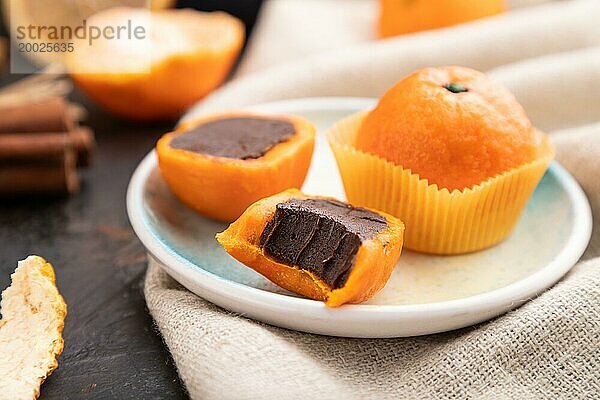 Trüffel Schokoladen Mandarinen Bonbons auf schwarzem Betonhintergrund und Leinenstoff. Seitenansicht  Nahaufnahme  selektiver Fokus