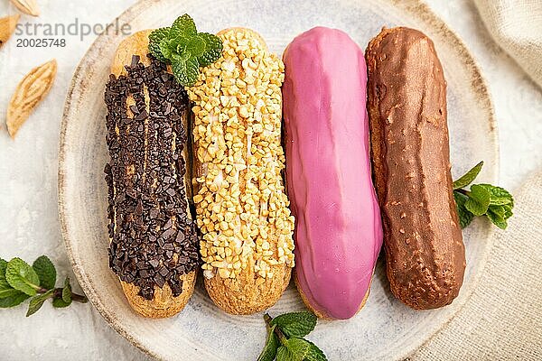 Set von Eclair  traditionelles französisches Dessert auf grauem Betonhintergrund und Leinenstoff. Ansicht von oben  Nahaufnahme  selektiver Fokus  Stillleben. Frühstück  Morgen  Konzept