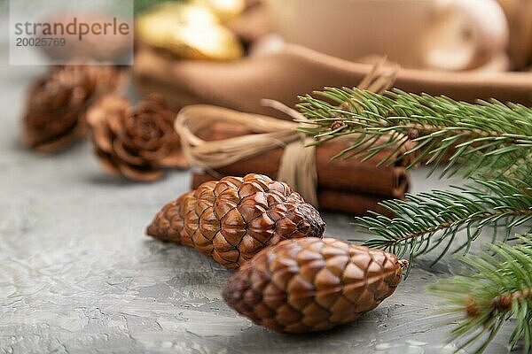 Weihnachten oder Neujahr Zusammensetzung. Dekorationen  Zapfen  Zimt  Tannen und Fichtenzweige  Tasse Kaffee  Wollschal auf einem grauen Betonhintergrund. Seitenansicht  Nahaufnahme  selektiver Fokus