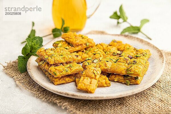 Traditionelles iranisches Dessert Sohan mit einem Glas grünem Tee auf einem grauen Betonhintergrund und Leinenstoff. Seitenansicht  Nahaufnahme  selektiver Fokus