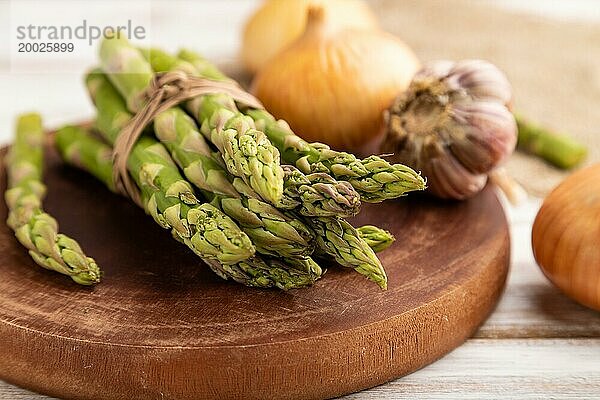 Strauß frischer grüner Spargel  Knoblauch  Zwiebel auf weißem Holzhintergrund. Seitenansicht  selektiver Fokus. Ernte  gesund  veganes Essen  Konzept