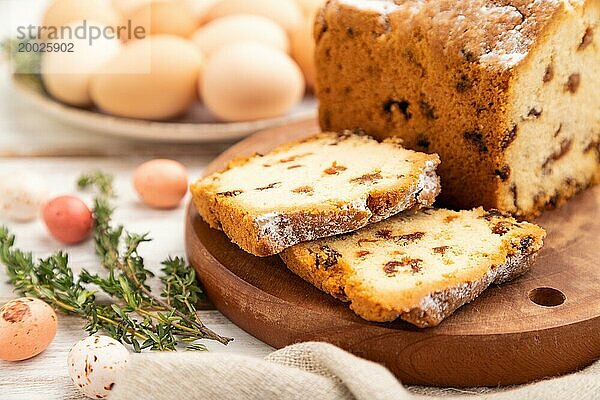 Hausgemachter Osterkuchen mit Rosinen und Eiern auf einem Teller auf einem weißen hölzernen Hintergrund und Leinenstoff. Seitenansicht  Nahaufnahme  selektiver Fokus