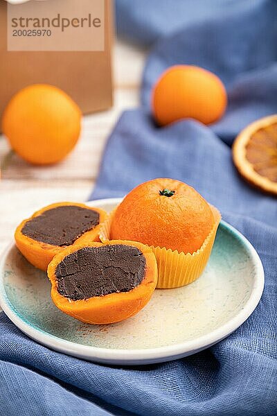 Trüffel Schokoladen Mandarinen Bonbons auf weißem Holzhintergrund und blauem Leinenstoff. Seitenansicht  Nahaufnahme  selektiver Fokus