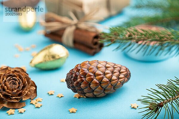 Weihnachten oder Neujahr Zusammensetzung. Dekorationen  Box  Zimt  Zapfen  Tanne und Fichte Zweige  auf einem blauen Papier Hintergrund. Seitenansicht  Nahaufnahme  selektiver Fokus