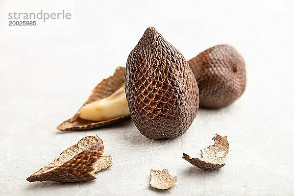 Salak oder Schlangenfrucht auf grauem Betonhintergrund. Seitenansicht  Nahaufnahme  selektiver Fokus. Tropisch  gesunde Ernährung  Sommer  exotisch  Minimalismus