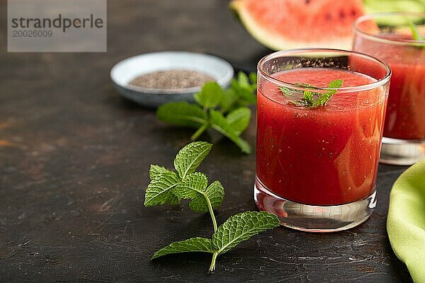 Wassermelonensaft mit Chiasamen und Minze im Glas auf einem schwarzen Betonhintergrund mit grünem Textil. Gesundes Getränk Konzept. Seitenansicht  Nahaufnahme  selektiver Fokus