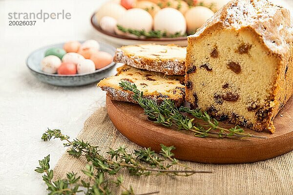 Hausgemachter Osterkuchen mit Rosinen und Eiern auf einem Teller auf einem grauen Betonhintergrund und Leinenstoff. Seitenansicht  selektiver Fokus  Nahaufnahme