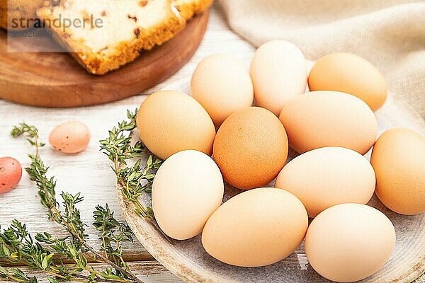 Hausgemachter Osterkuchen mit Rosinen und Eiern auf einem Teller auf einem weißen hölzernen Hintergrund und Leinenstoff. Seitenansicht  Nahaufnahme  selektiver Fokus