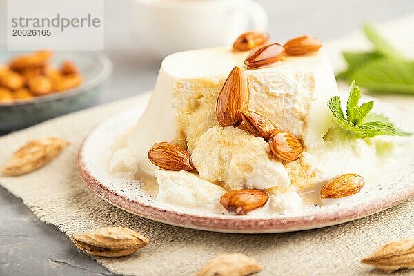 Ricotta Käse mit Honig und Mandeln auf grauem Betonhintergrund und Leinenstoff. Seitenansicht  Nahaufnahme  selektiver Fokus