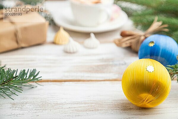 Weihnachten oder Neujahr Rahmen Zusammensetzung. Dekorationen  Box  Kugeln  Zimt  Bänder  Tannen und Fichtenzweige  Tasse Kaffee  auf einem weißen Holzhintergrund. Seitenansicht  copy space  selektiver Fokus